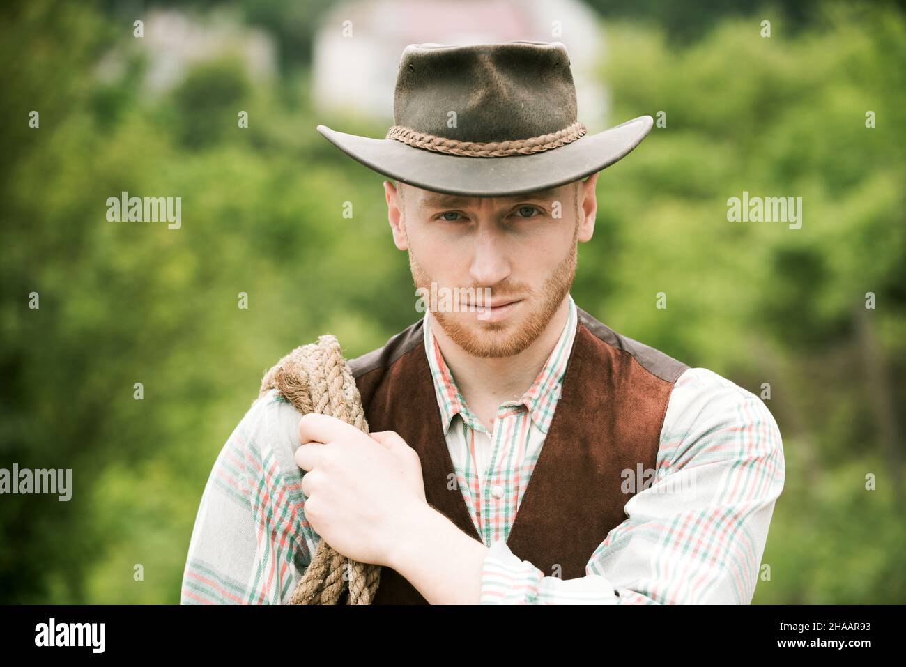 Chico vaquero. Propietario del rancho. Concepto de trabajador agrícola y  agrícola. Vaquero con cuerda de lazo sobre fondo verde. Hombre guapo con  sombrero de vaquero y estilo rústico Fotografía de stock -