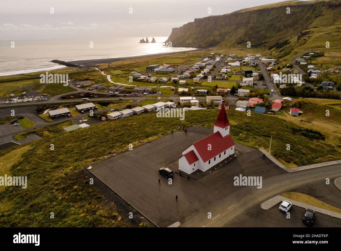 Vista aérea de la iglesia en Vik, en el sur de Islandia, rodó mirando al mar con las famosas formaciones rocosas en el fondo Foto de stock