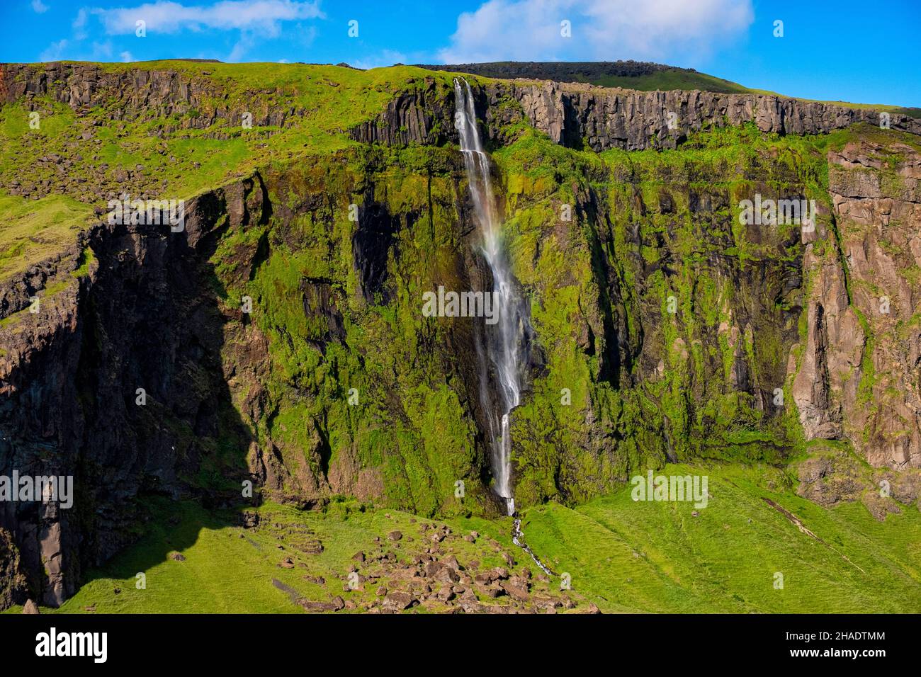 Una cascada en un pequeño arroyo que cae de altos acantilados en las montañas Eyjafjoll en el sur de Islandia, cayendo 100 metros al suelo Foto de stock