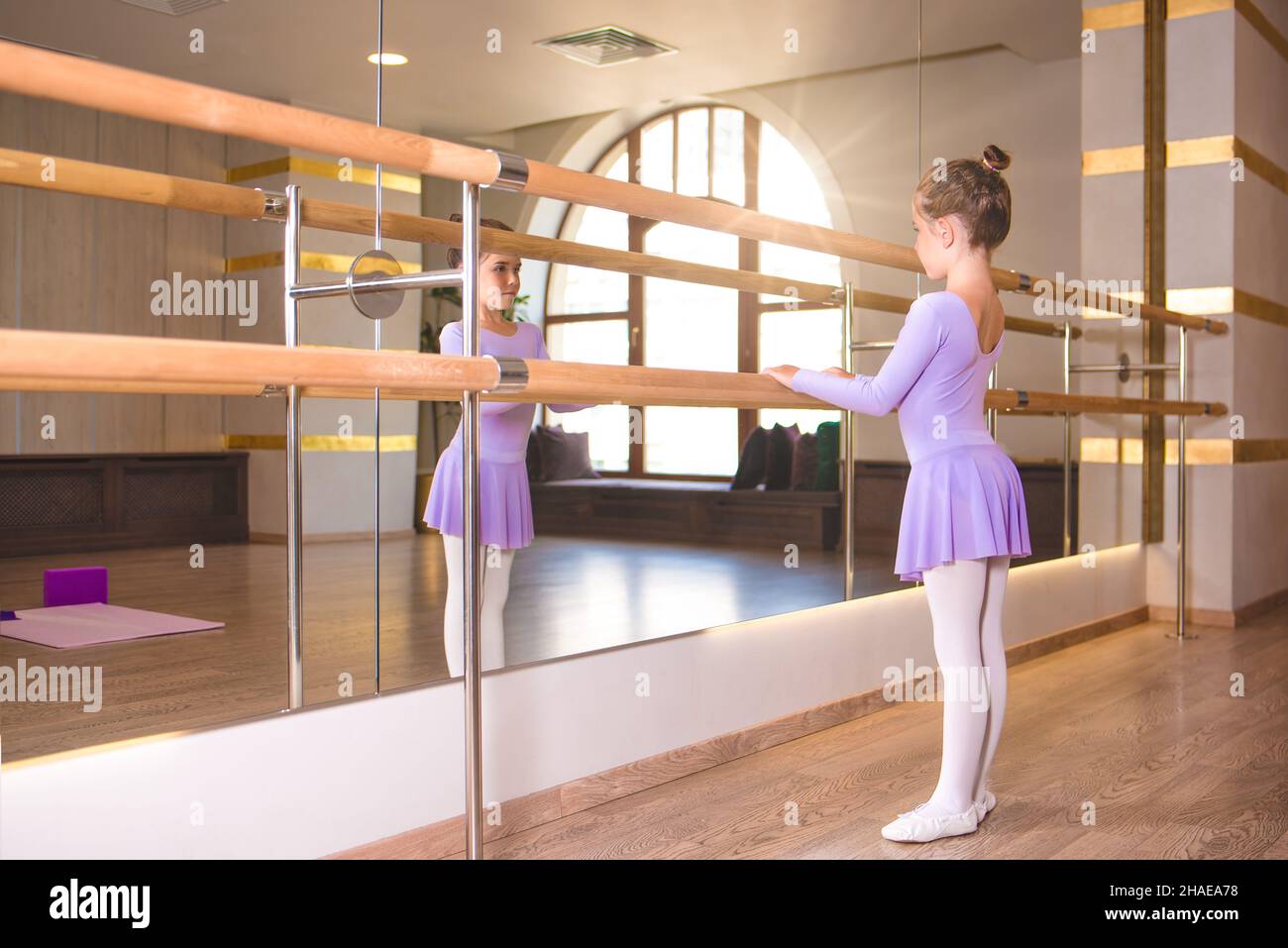 la niña lleva pointe en clase de ballet cerca del marco y espejo grande Foto de stock