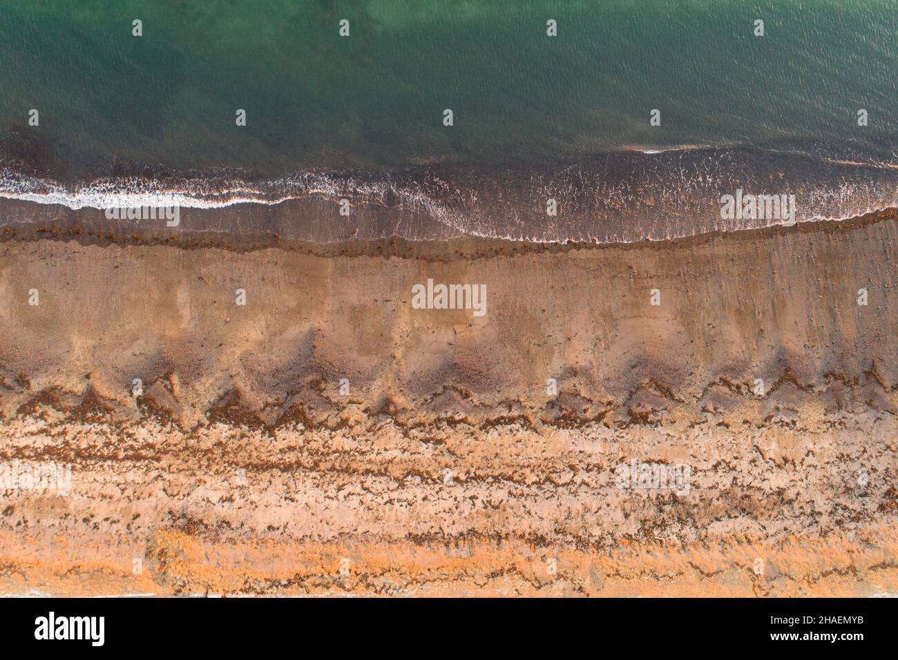 Disparo aéreo de una arena blanca de playa con océano verde, tiro mirando hacia abajo Foto de stock