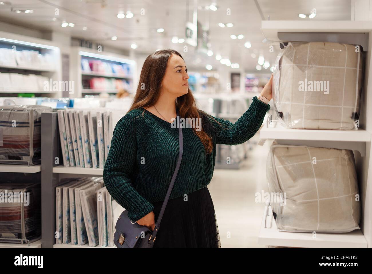Mujer joven enfocada haciendo compras en el centro comercial de la tienda en  el departamento de ropa de cama, mirando pensivamente el juego de ropa de  cama, pensando en cambiar el estilo