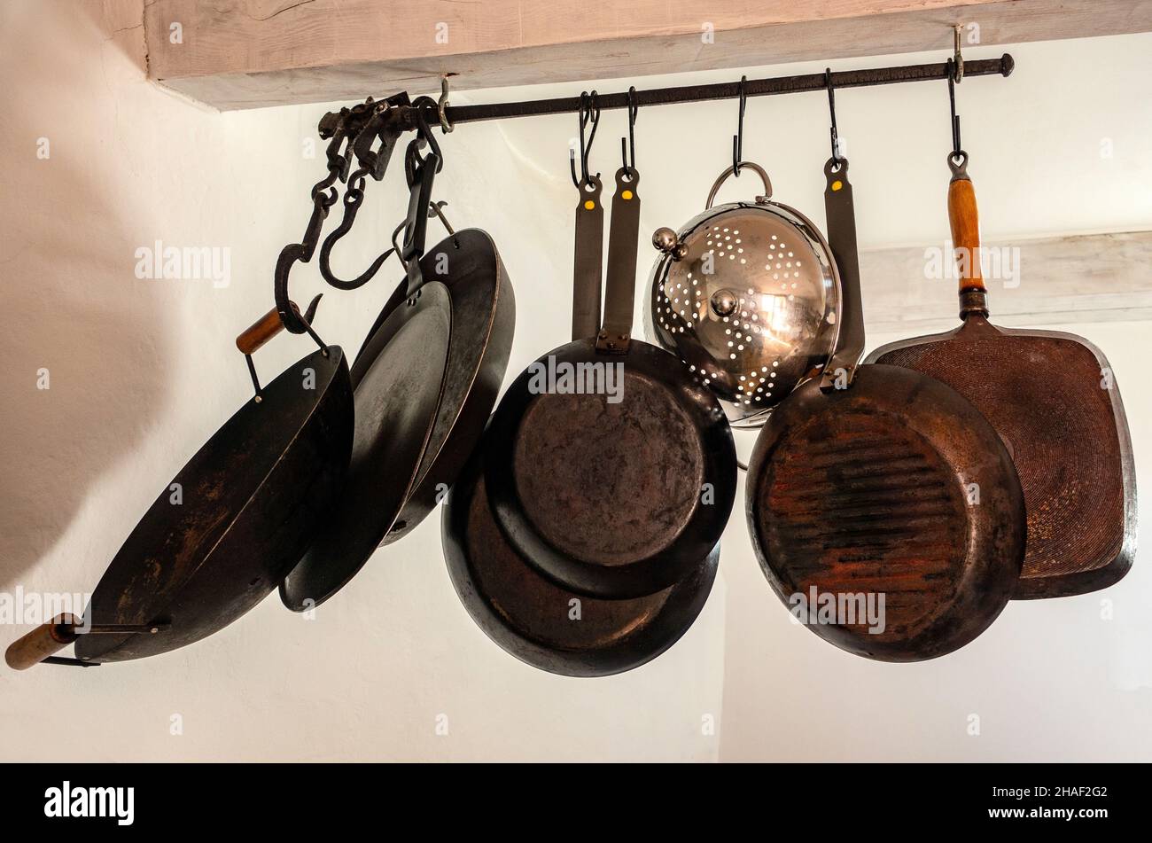 Batería de cocina, cocina cucharas, cucharones, ollas de cobre, las rodajas  de pescado, afilado de cuchillas y de utensilios de cocina de acero  colgando de un soporte de pared Fotografía de stock 