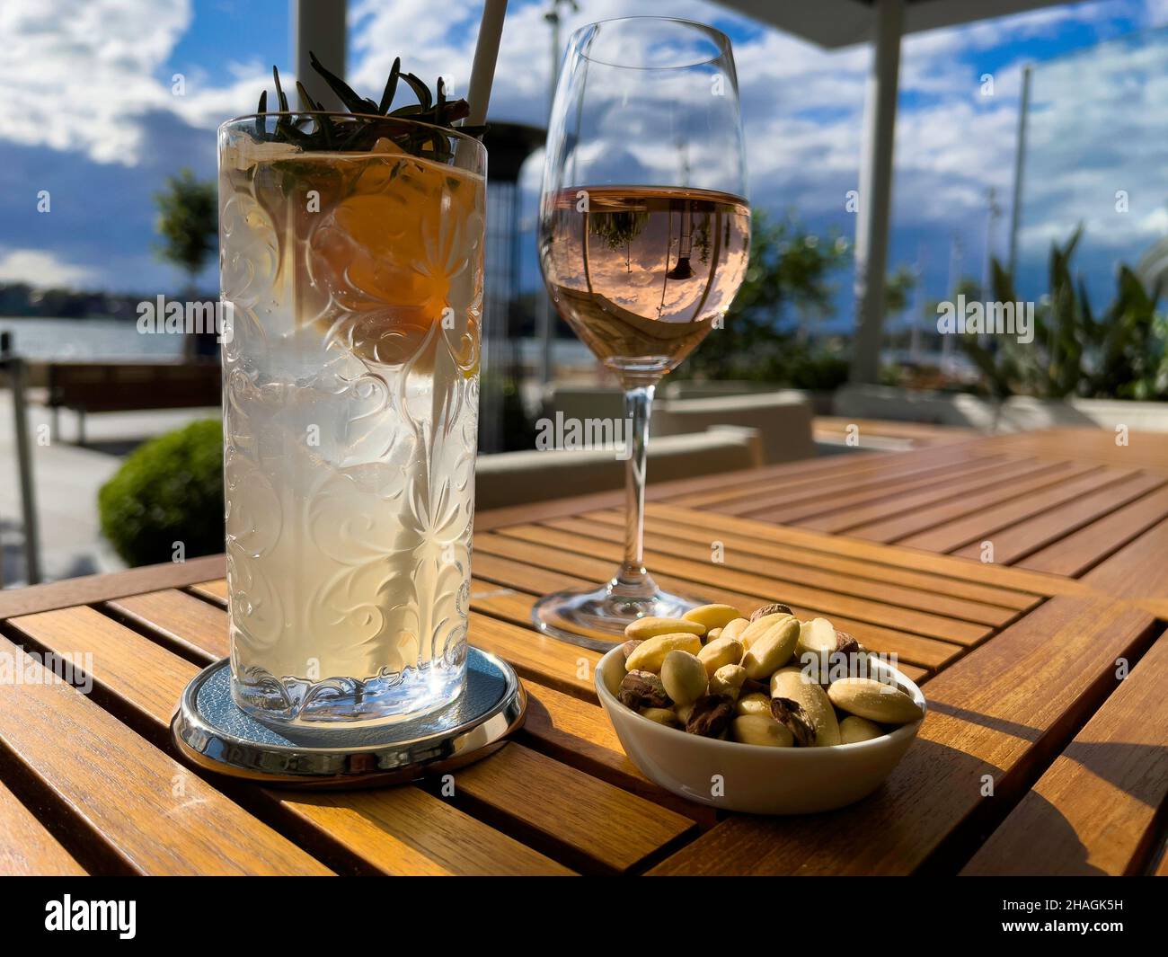 Dos copas de vino y cócteles con reflejos de sol y cielo en una mesa en