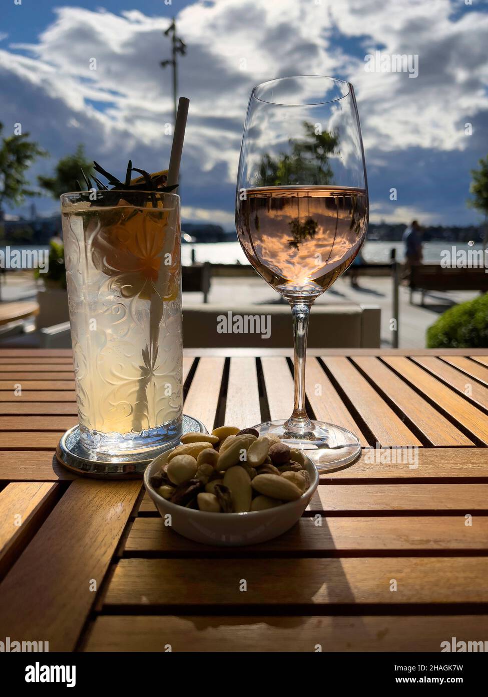 Dos copas de vino y cócteles con reflejos de sol y cielo en una mesa en