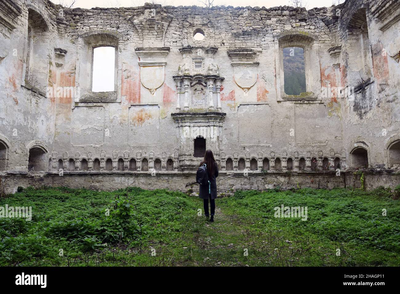 Joven chica esbelta con largo cabello rubio examina las ruinas de una antigua sinagoga. Viajero con mochila. Moldavia. Rashkov. Enfoque selectivo. Copiar Foto de stock