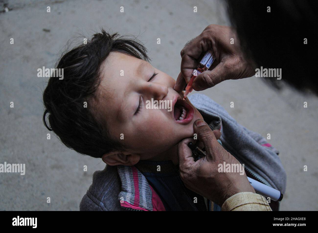 RAWALPINDI, Pakistán - diciembre de 13: Un trabajador de salud administra la vacuna contra la poliomielitis a un niño durante una campaña contra la poliomielitis en Rawalpindi el 13 de diciembre de 2021 Foto de stock