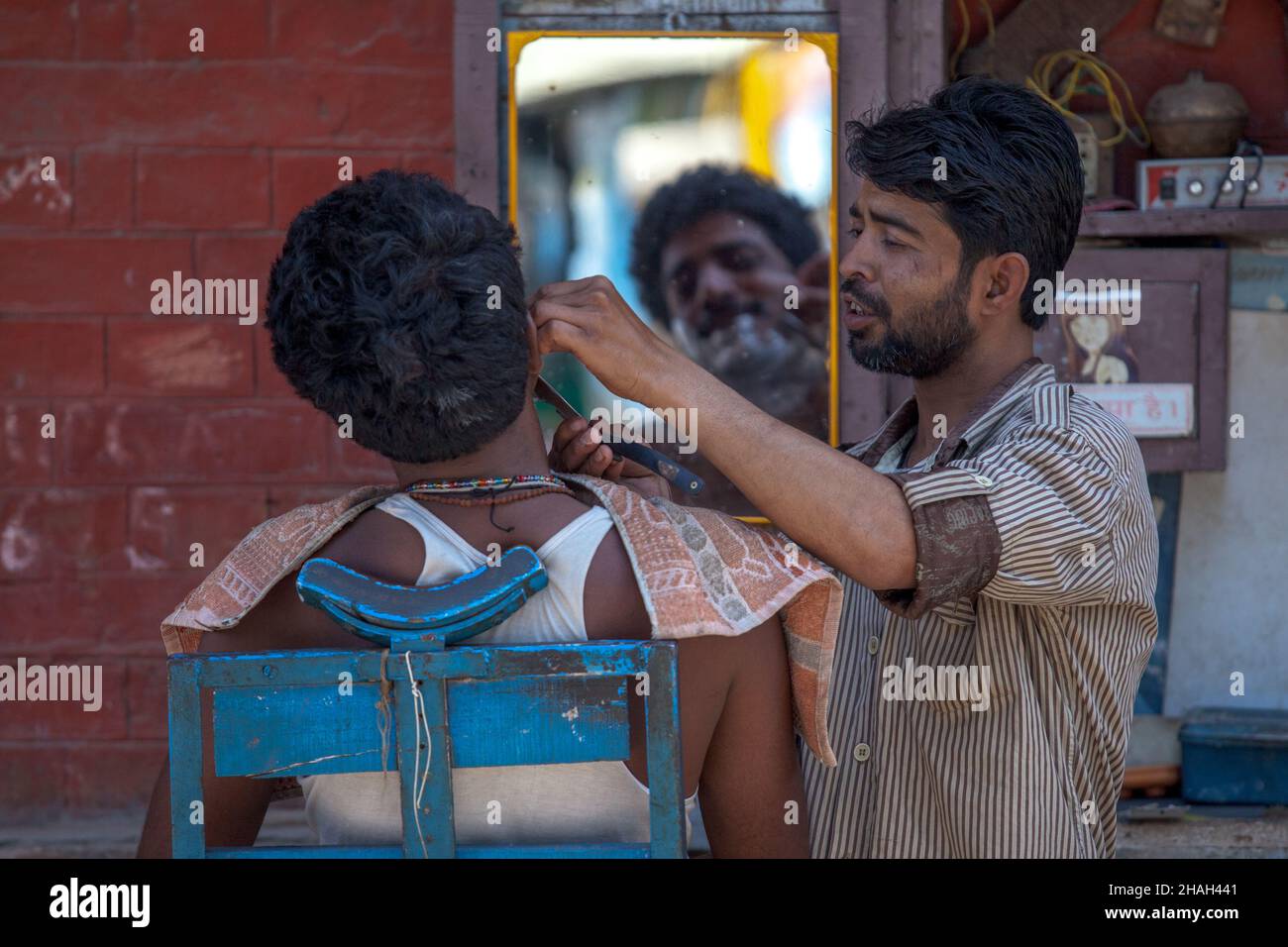 un joven indio se afeita en la barbería de la calle en varanasi Foto de stock
