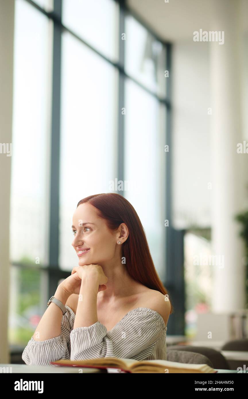 Mujer sentada en la mesa mirando a un lado Foto de stock