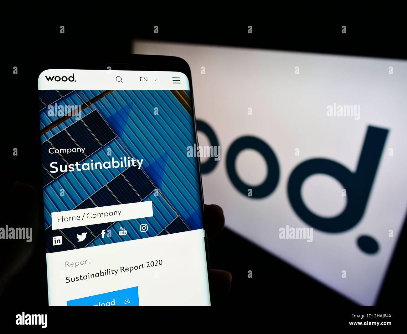 Persona que sostiene el celular con el sitio web de la compañía