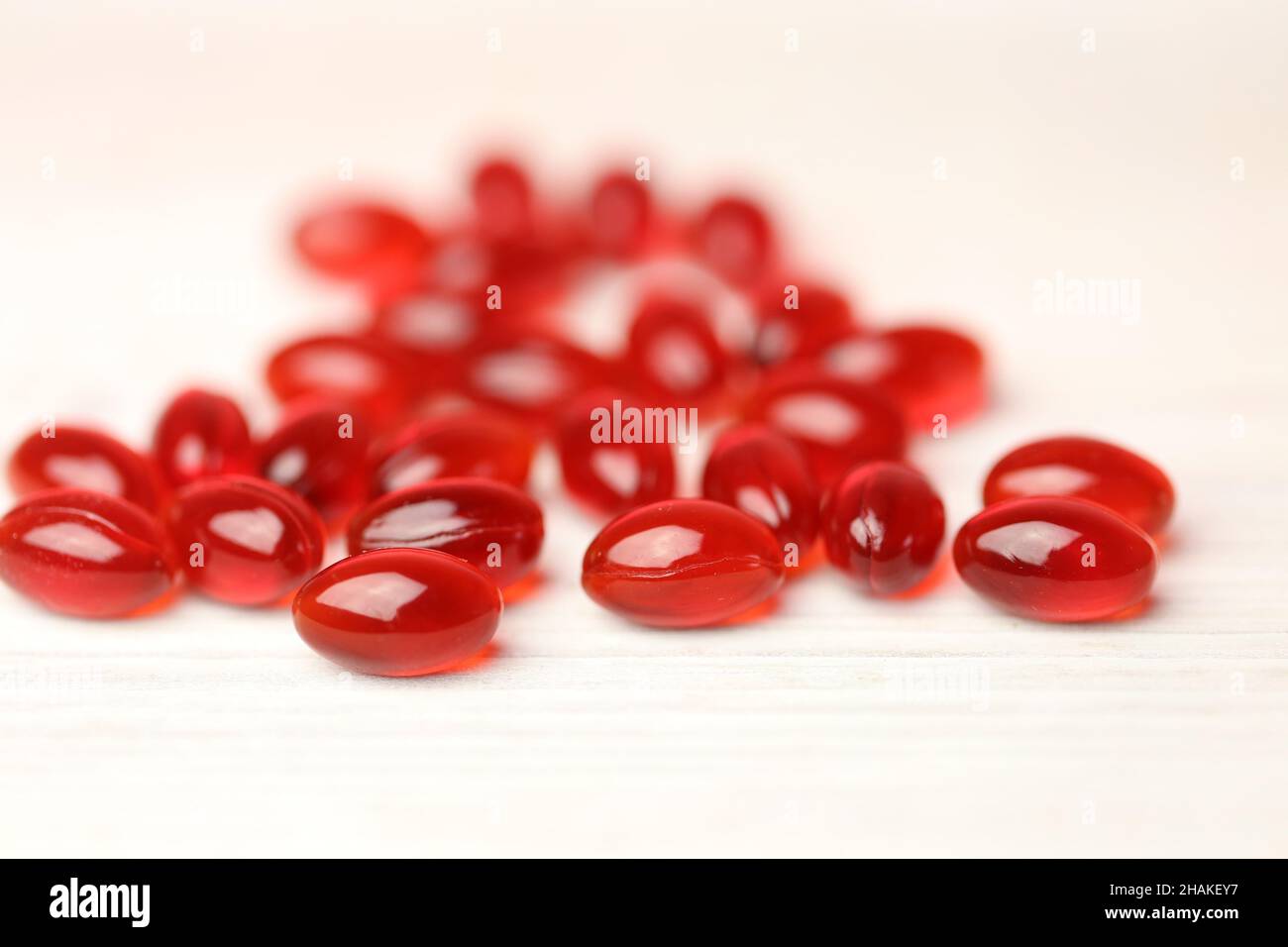 Aceite de krill cápsulas de gelatina roja sobre fondo blanco de madera .ácidos grasos omega Foto de stock