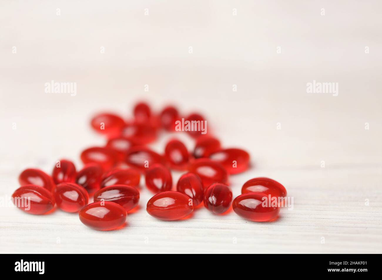 Aceite de krill cápsulas de gelatina roja sobre fondo blanco de madera. Suplementos naturales y vitamina Foto de stock