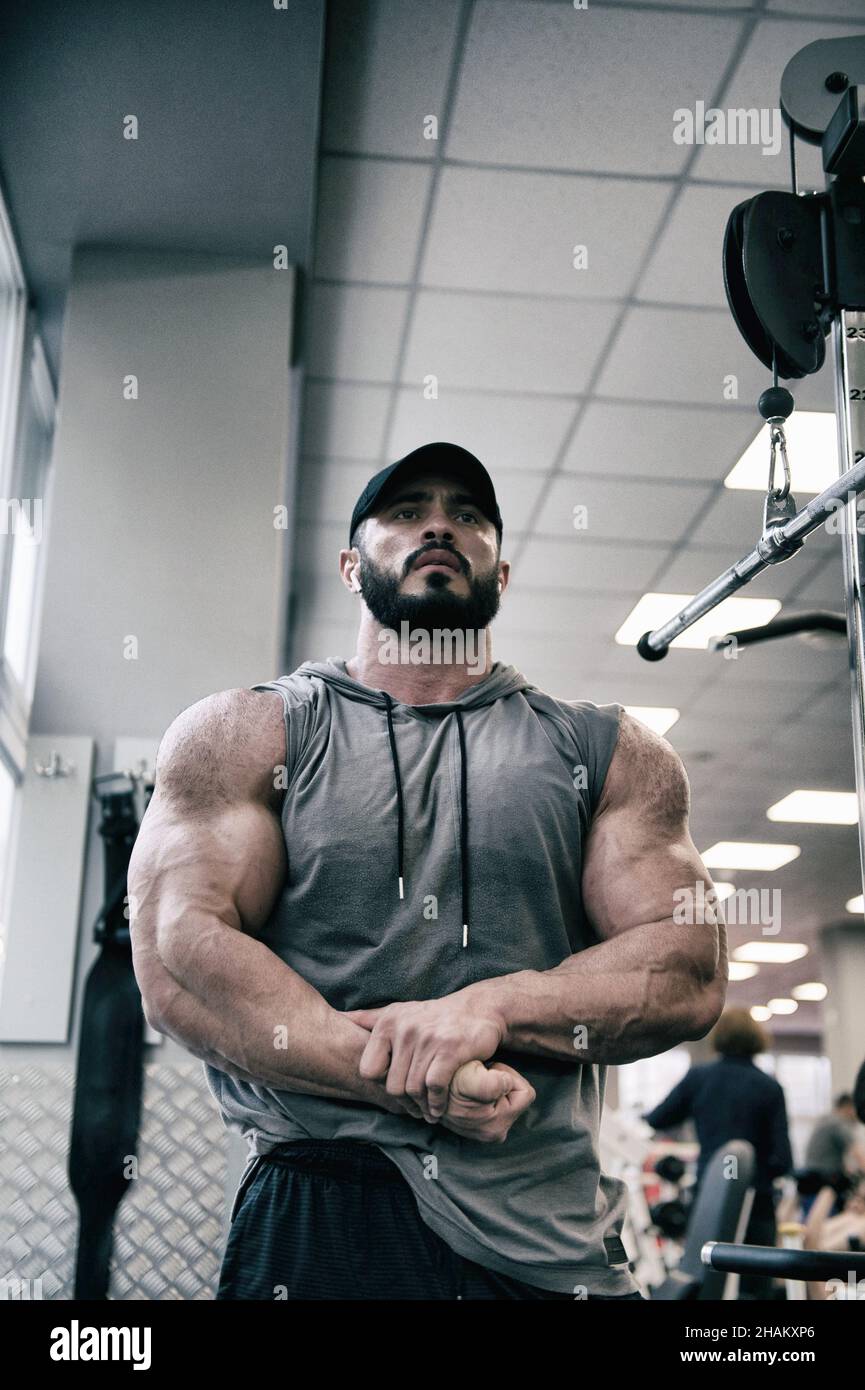 hombre joven fuerte con barba mostrando músculos fuertes en el gimnasio interior Foto de stock