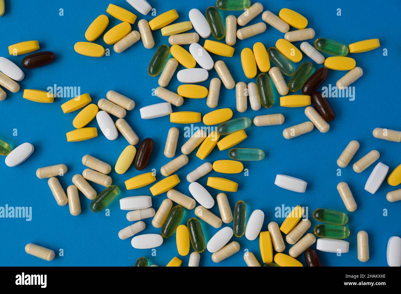 muchas pastillas de gel y cápsulas de la farmacia de la medicina en la superficie azul Foto de stock