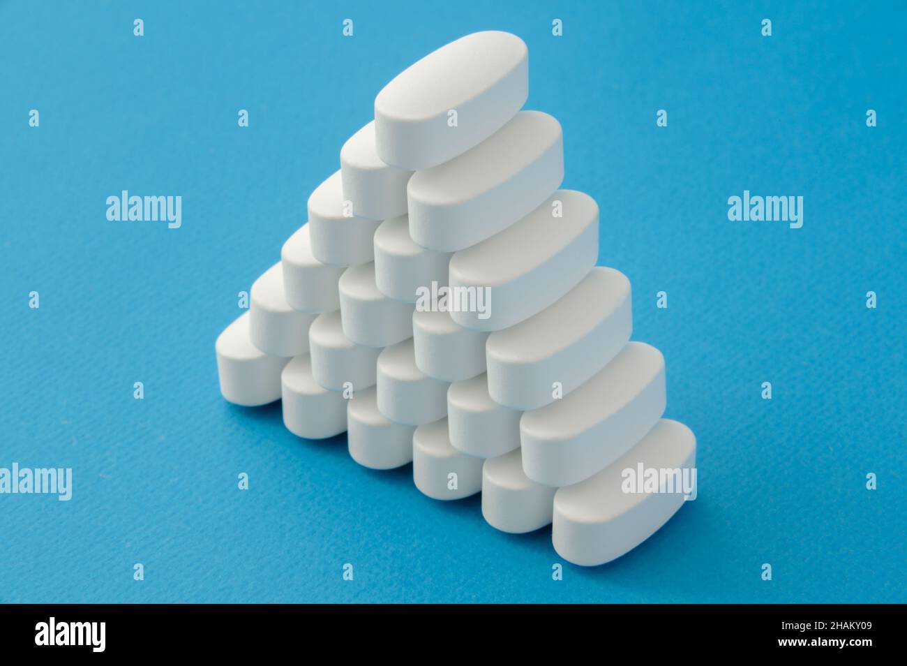 muchas tabletas blancas farmacológicas píldoras sobre fondo azul con copia espacio Foto de stock