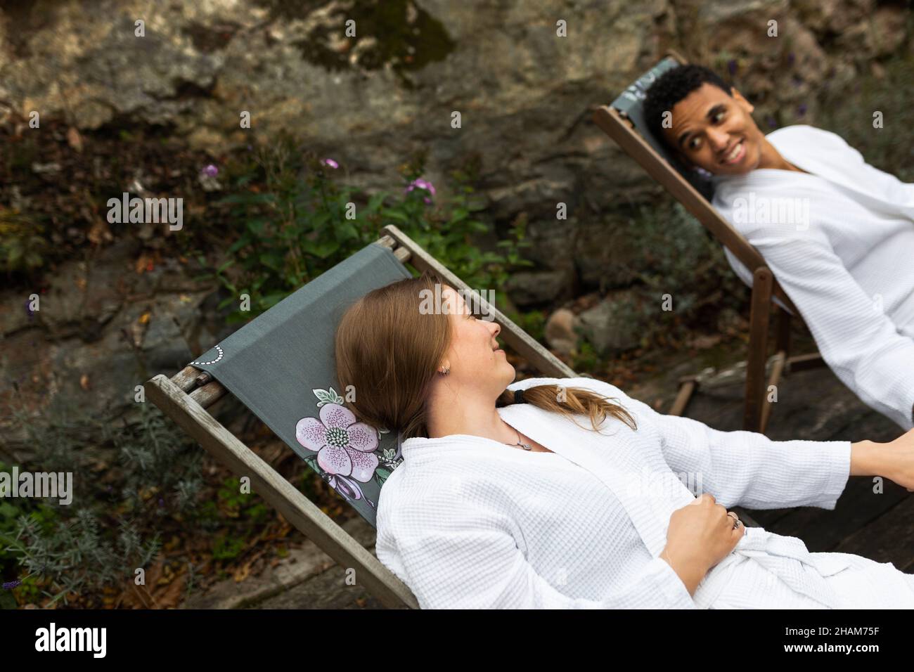 Una pareja en los albornoces relajándose en las sillas al aire libre Foto de stock
