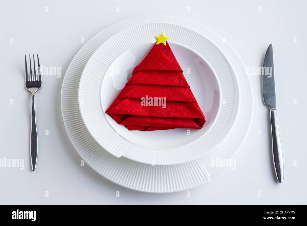 Servilleta roja doblada en forma de árbol de pino en un plato con  cubertería set.Christmas o concepto de Año Nuevo Fotografía de stock - Alamy