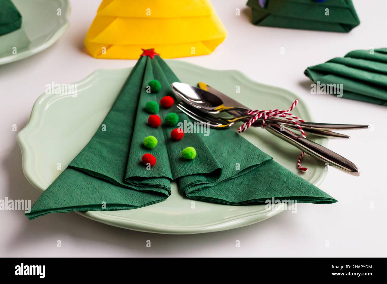 Servilletas de papel de color verde dobladas en forma de árbol de Navidad  en un plato con cubertería y otras servilletas Fotografía de stock - Alamy