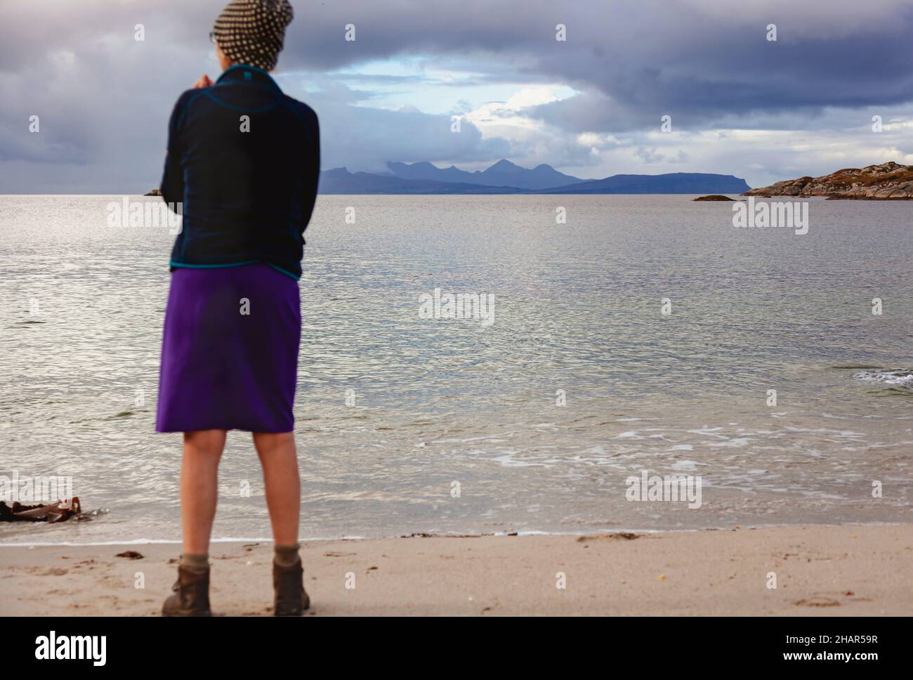 Un visitante que disfruta de las vistas a las pequeñas islas desde una de las playas de arena blanca de Ardtoe en la península de Ardnamurchan, en el oeste de Escocia Foto de stock