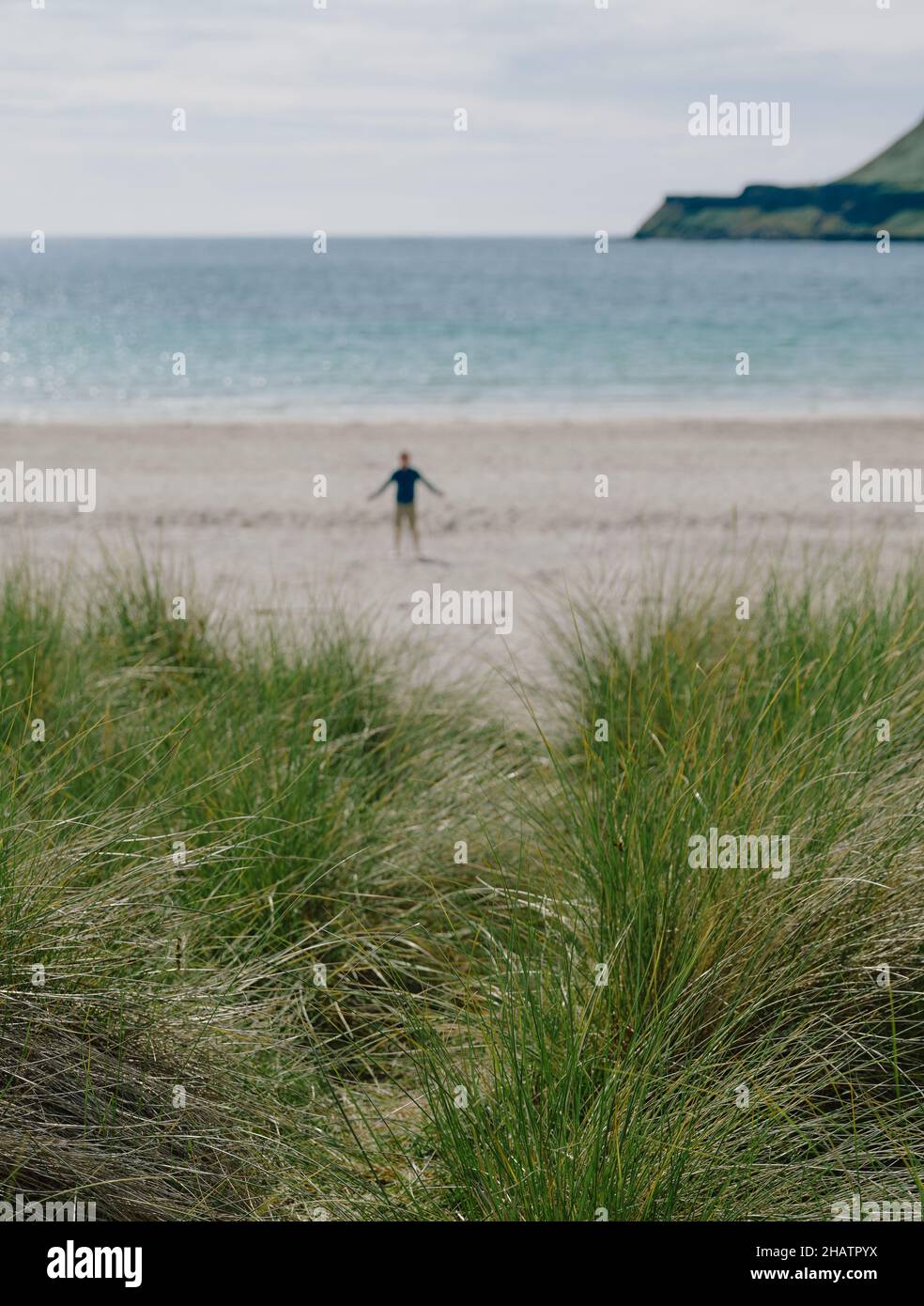 Figura solitaria en una playa escocesa con dunas de arena de hierba Marram y paisaje de verano en la isla de Mull, Inner Hebrides, Escocia Reino Unido - escapada Foto de stock
