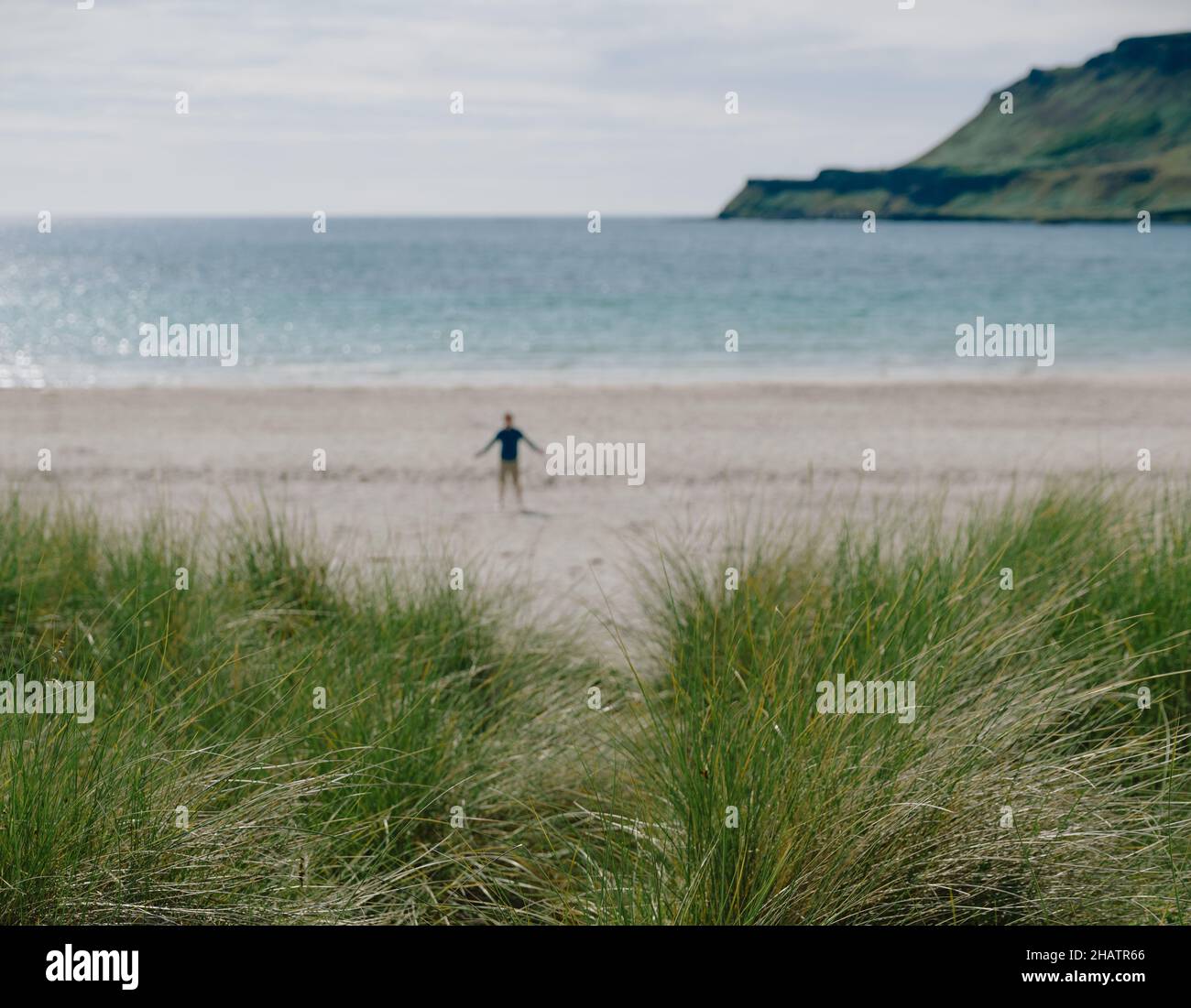 Figura solitaria en una playa escocesa con dunas de arena de hierba Marram y paisaje de verano en la isla de Mull, Inner Hebrides, Escocia Reino Unido - escapada Foto de stock