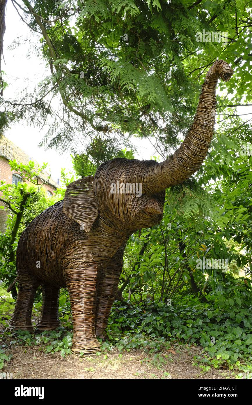 Escultura de mimbre de un elefante entre los árboles en los jardines Hellens Manor, mucho Markle, Herts., Reino Unido Foto de stock