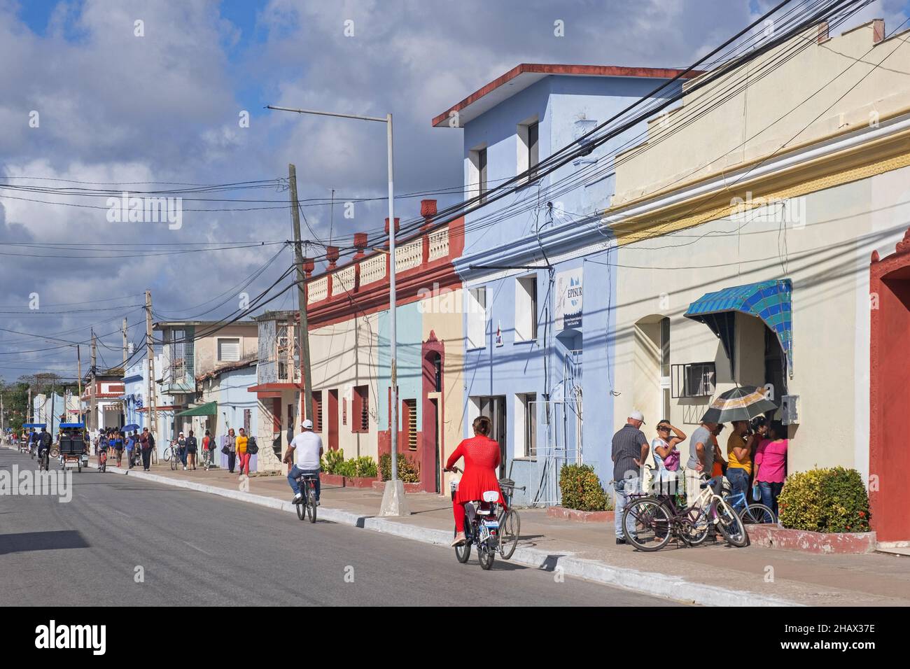 Cubanos haciendo cola frente a una tienda de colores pastel en la calle principal de la ciudad Guáimaro en la parte sur de la provincia de Camagüey, Cuba, Caribe Foto de stock