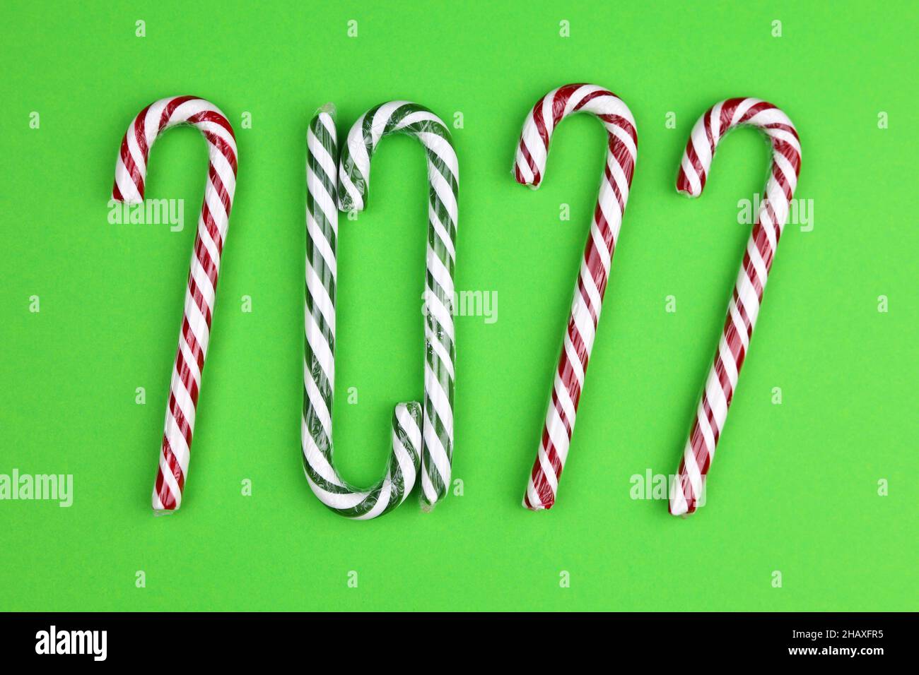 Bastones de caramelo de Navidad sobre fondo verde. Inscripción 2022 de dulces tradicionales, celebración de Año Nuevo Foto de stock
