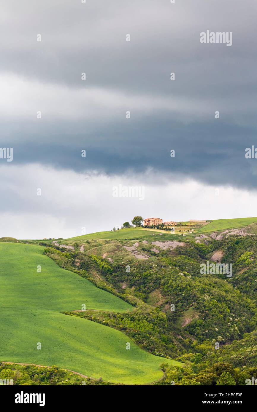 Granja en una colina con campos y nubes oscuras tormentas Foto de stock