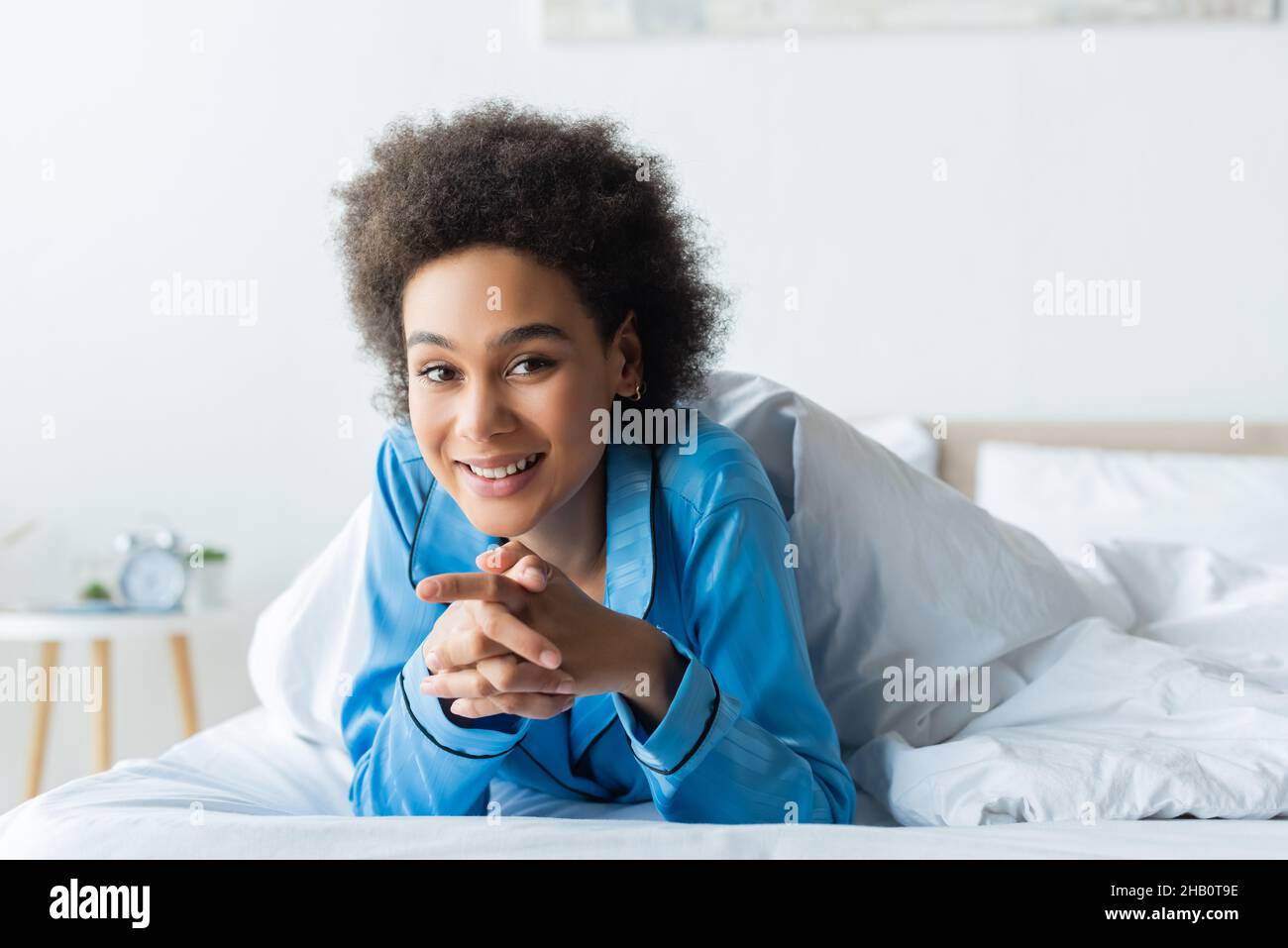 feliz mujer afroamericana en pijamas acostada en la cama Foto de stock