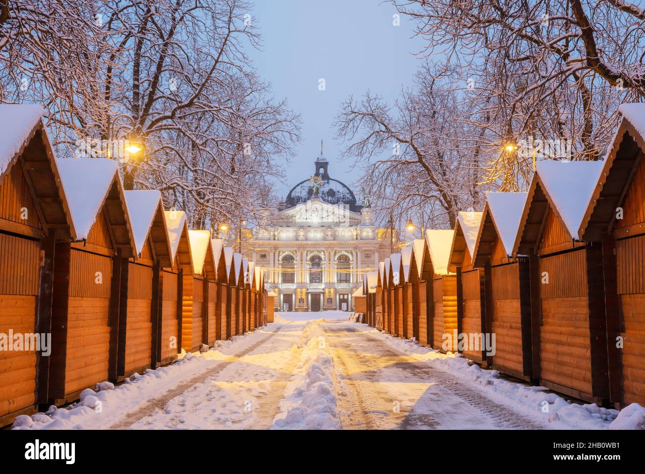 Solomiya Krushelnytska Lviv State Academic Theatre of Opera and Ballet in winter time. Quiosco de madera de la feria de Navidad en una fila con la luz de la ciudad en la mañana Foto de stock