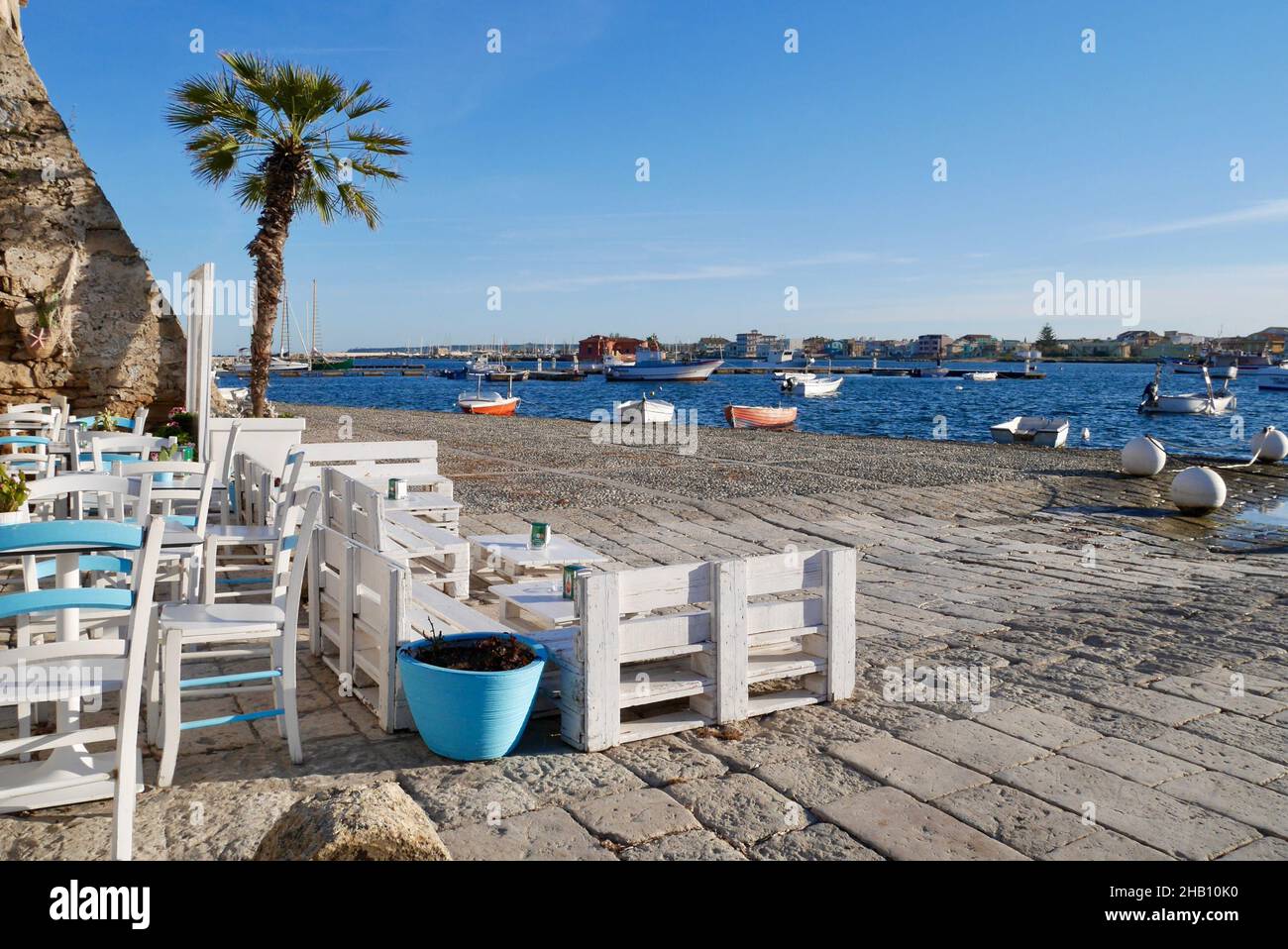 Encantadora zona de estar al aire libre con preciosas vistas al mar y a los barcos de pesca. Marzamemi, Provincia de Siracusa, Sicilia. Foto de stock