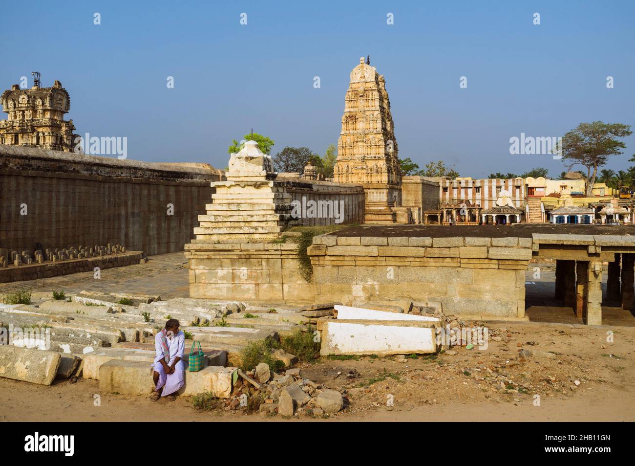 Hampi, Karnataka, India: Un hombre se sienta fuera del Templo de Sree Virupaksha del siglo 7th. Se cree que funciona ininterrumpidamente desde su inicio en Foto de stock