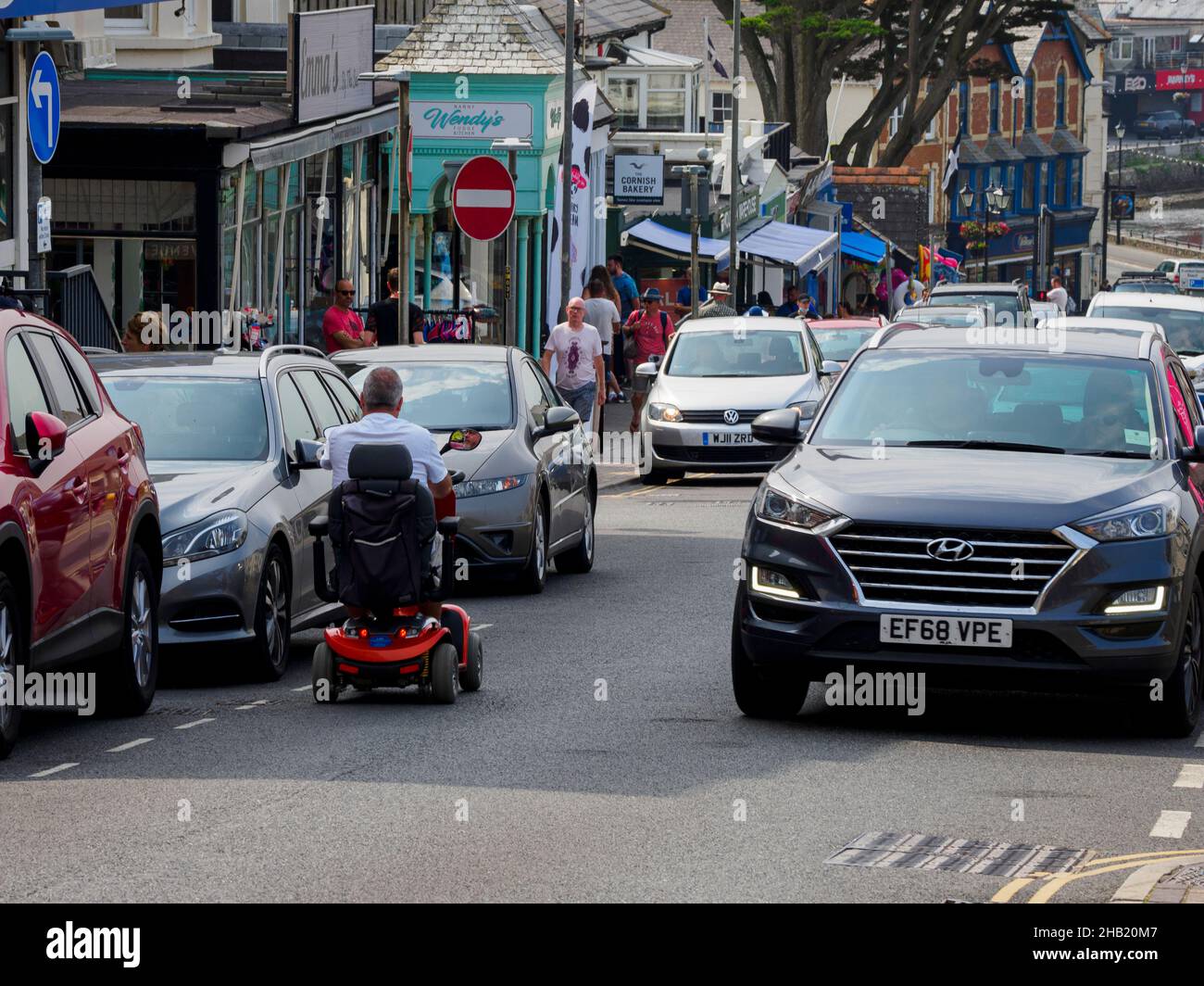 Hombre en scooter de la movilidad que va el camino equivocado en una calle de un solo sentido, Bude, Cornwall, Reino Unido Foto de stock