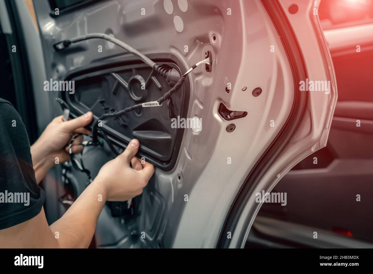 El trabajador del servicio de automóviles desmonta la puerta del coche para el cierre de la reparación. Foto de stock