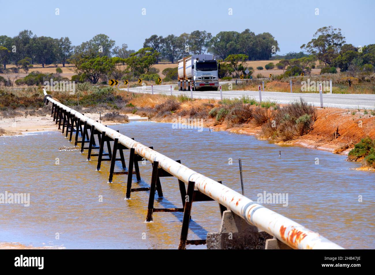 Cross country water pipe en stands cruzando el lago de sal con un camión que pasa, Wongan Hills, Australia Occidental Foto de stock