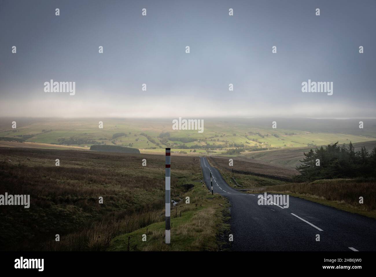 En una carretera desierta en la zona de páramos de Northumberland que emerge de la espesa niebla otoñal Foto de stock