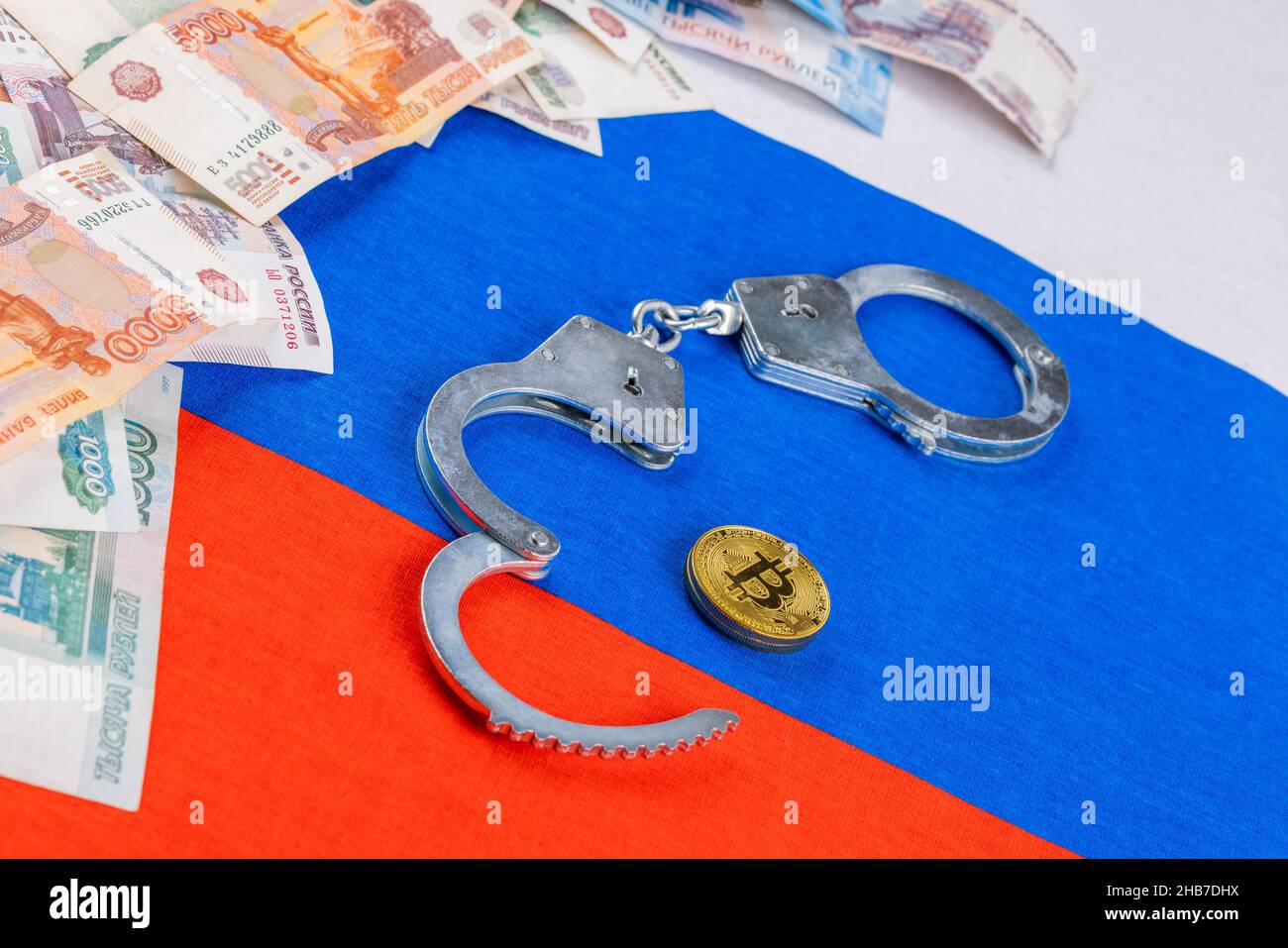 pila de papel ruso rublos moneda y moneda de bitcoin shiner encadenado con esposas en el fondo de la bandera rusa - cripto prohibición concepto de ley Foto de stock