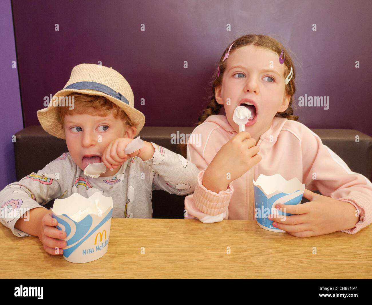 Dos niños pequeños comiendo helado en el restaurante McDonalds, Reino Unido Foto de stock