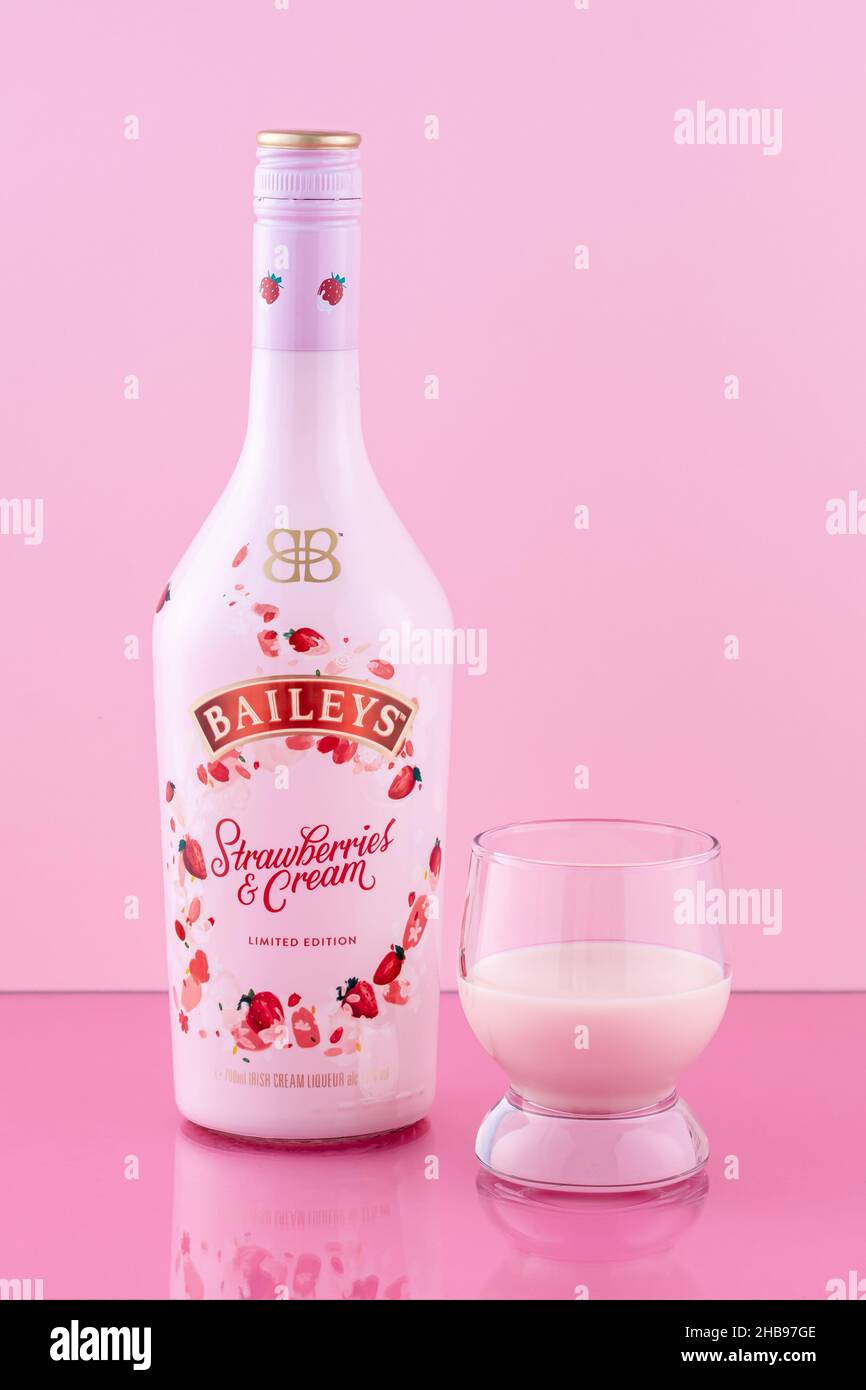 Una botella de Baileys con vidrio. Fresas y crema. Edición limitada. Licor sobre fondo rosa. Bebida alcohólica. Editorial ilustrativa Foto de stock