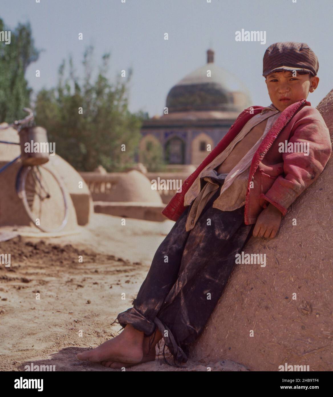 Un niño uygur se encuentra frente al mausoleo de Aba Khoja, cerca de Kashgar, China, en 1988. Foto de stock