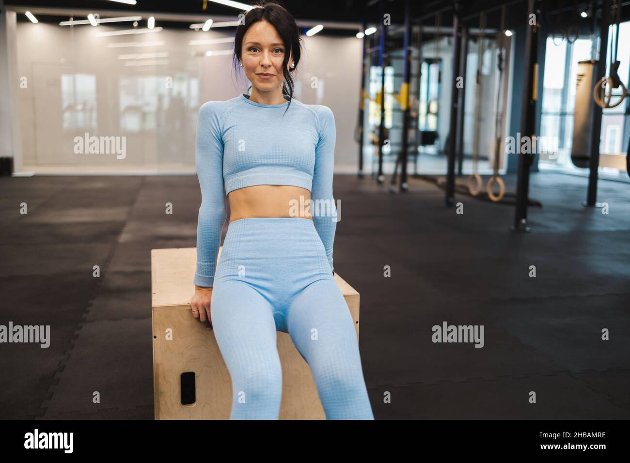 Mujer de ropa deportiva azul haciendo ejercicios de tríceps en madera crossfit caja de salto en el gimnasio Foto de stock