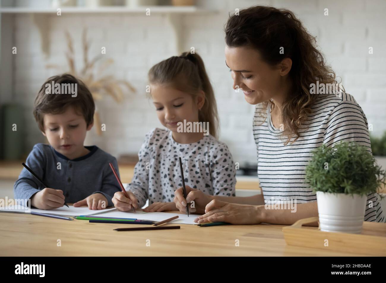 Sonriente madre y niños pequeños dibujando con lápices de colores Foto de stock