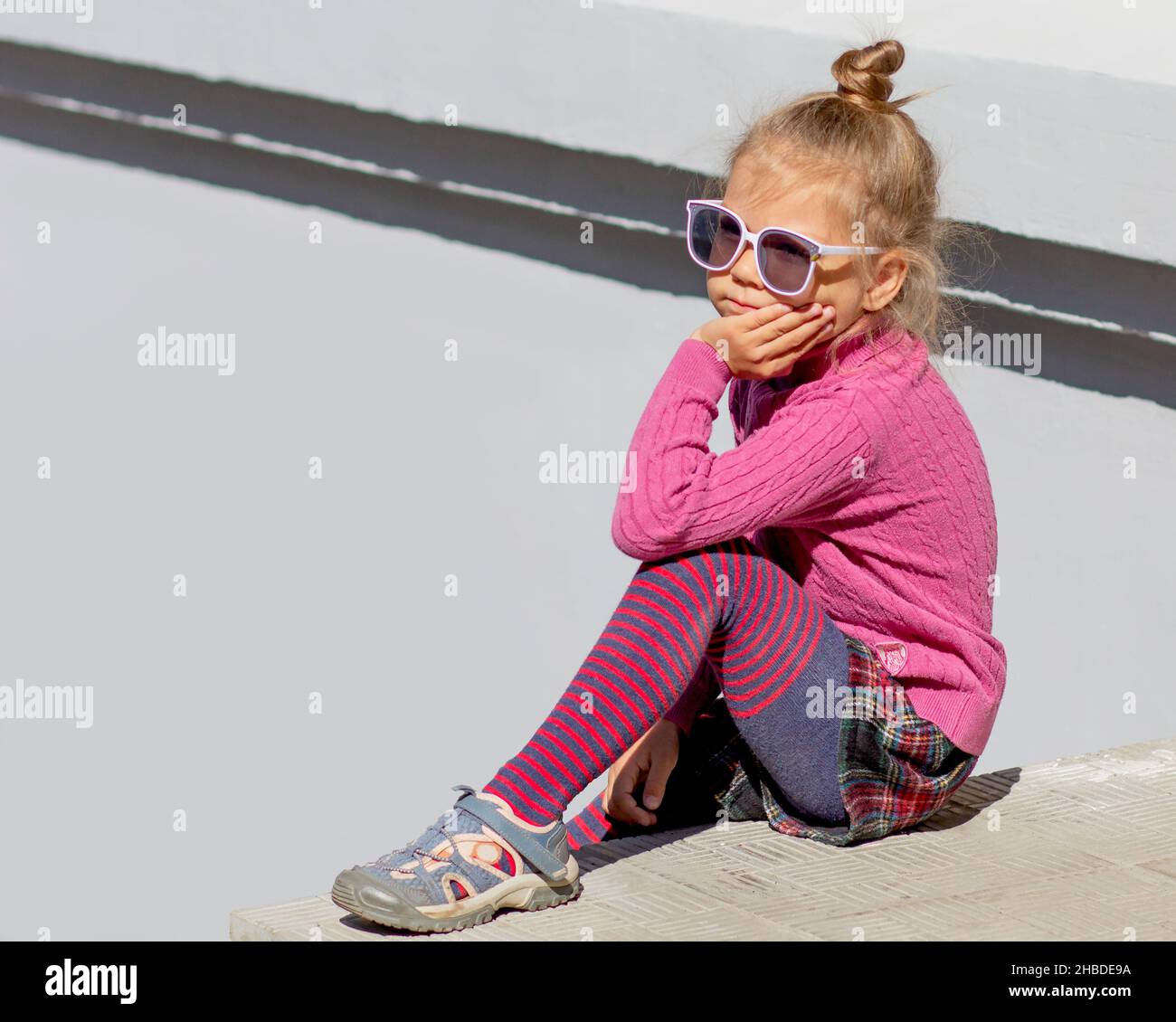 Lindo pensamiento de moda y soñando niña de 5 años sentado sosteniendo su barbilla y mirando a un lado en gafas de fuera en verano Fotografía de stock Alamy