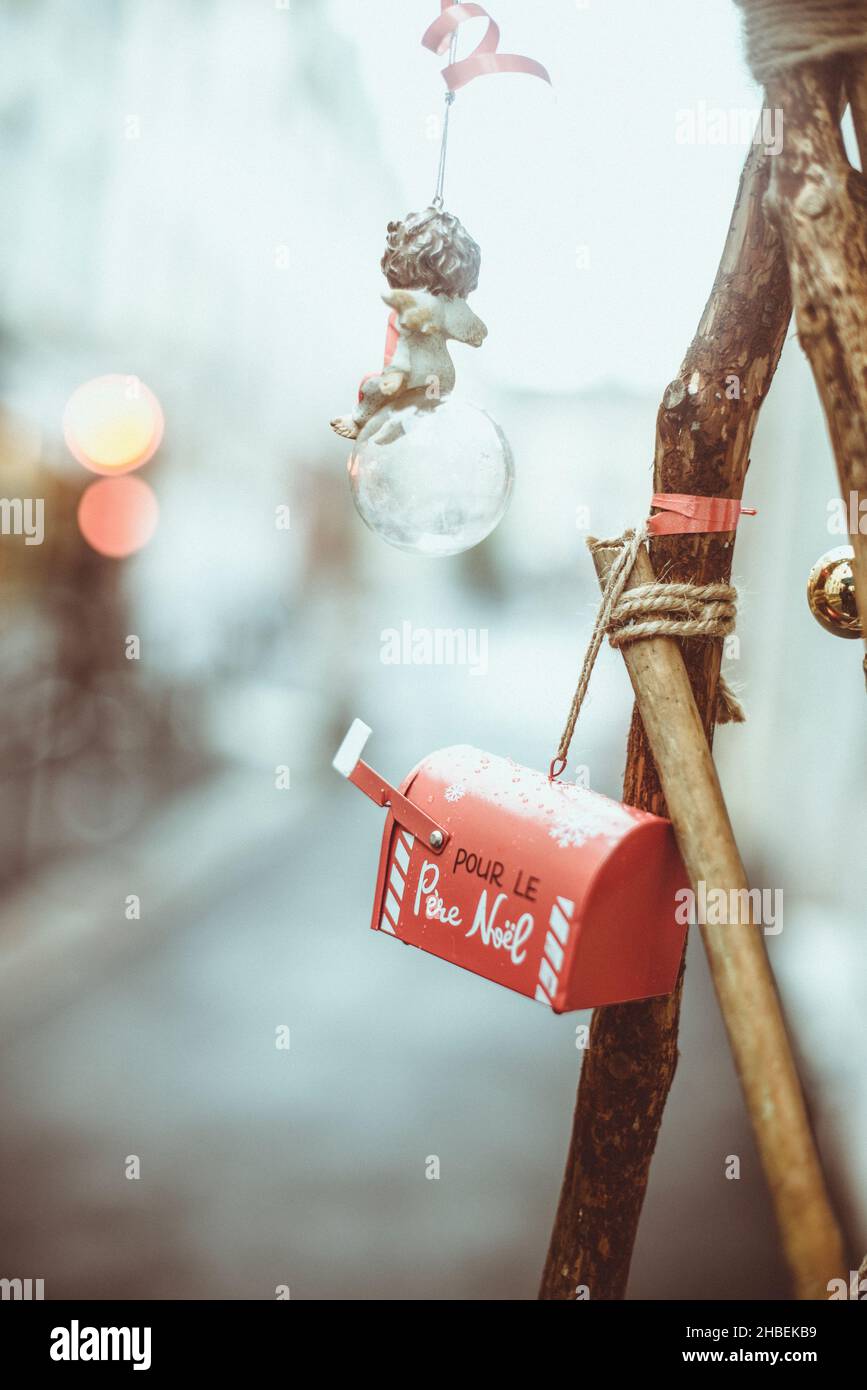 Adornos navideños de ángel, bola y letterbox colgando en una rama al aire libre Foto de stock