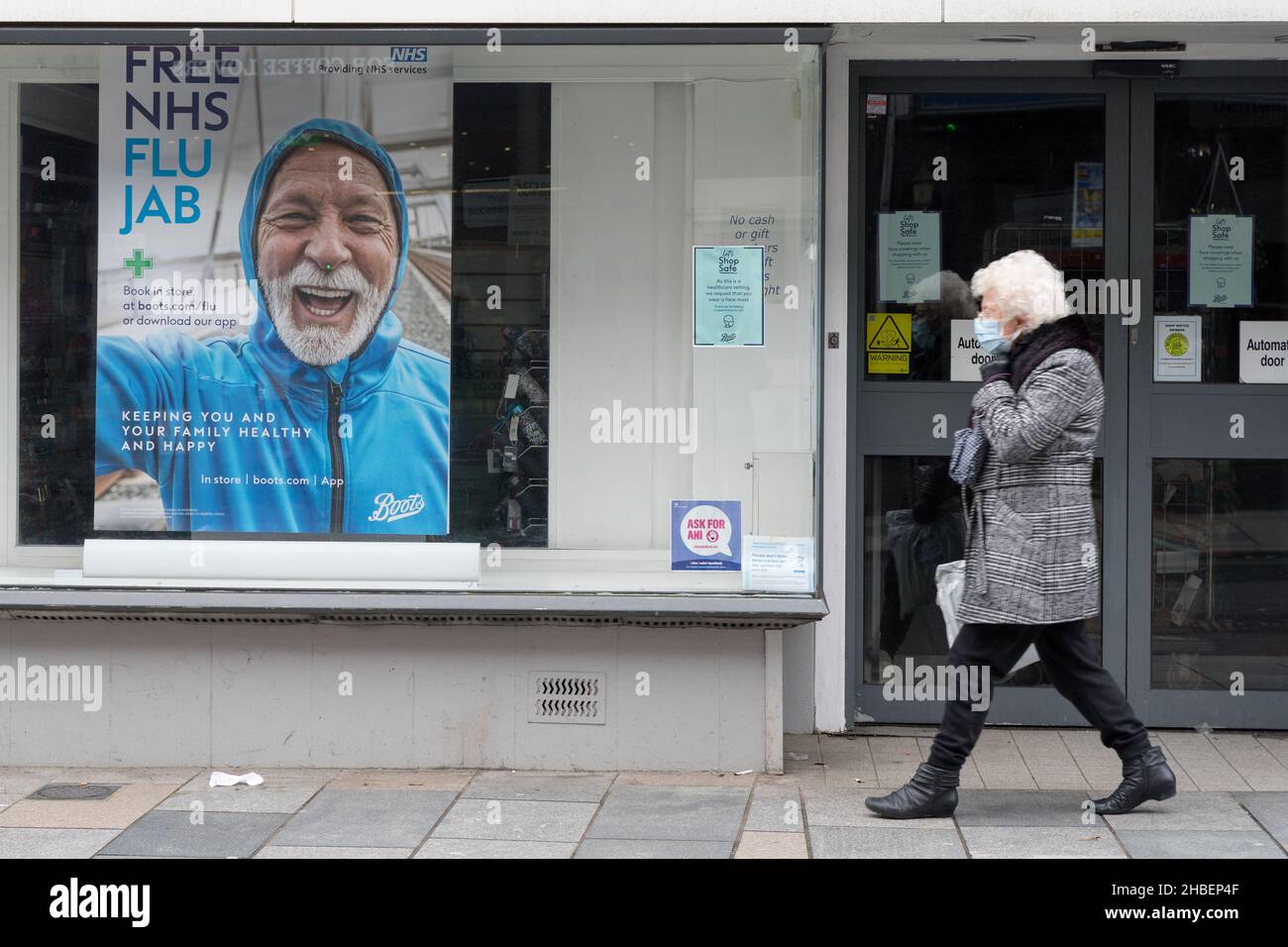 Mujer con cobertura de cara Pasar un cartel para la gripe de invierno jab, gratis para grupos de personas elegibles Bexley Londres Inglaterra Foto de stock