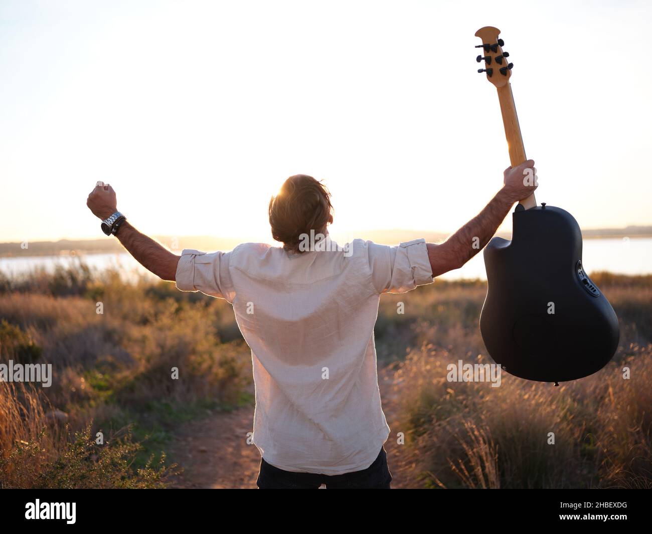 el hombre gritando al cielo su libertad mientras sostiene una guitarra en su mano hacia arriba Foto de stock