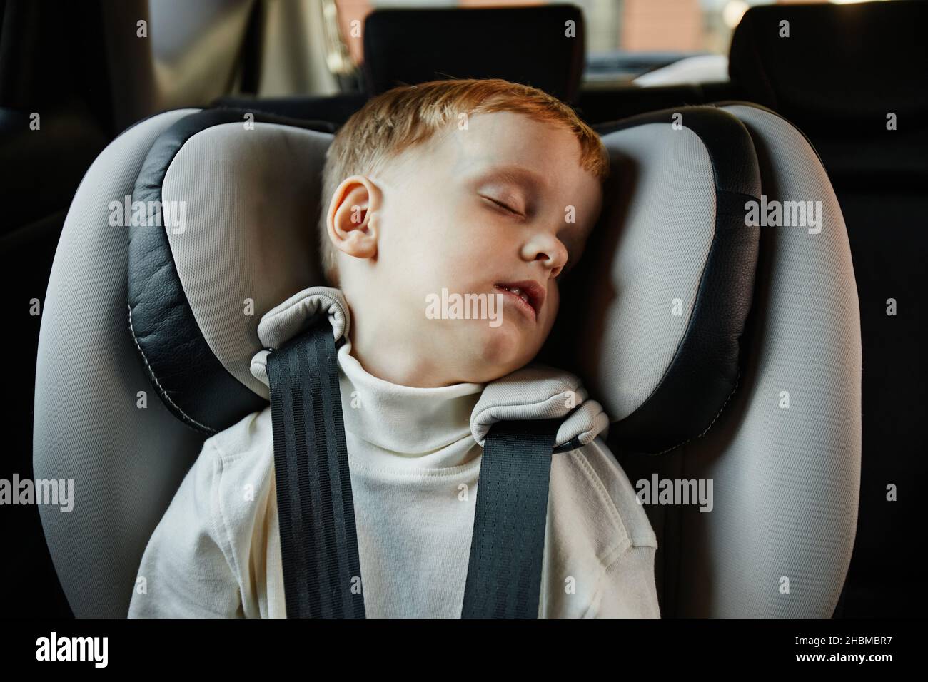 Retrato de niño pequeño lindo durmiendo en el asiento del coche de la familia, espacio de copia Foto de stock