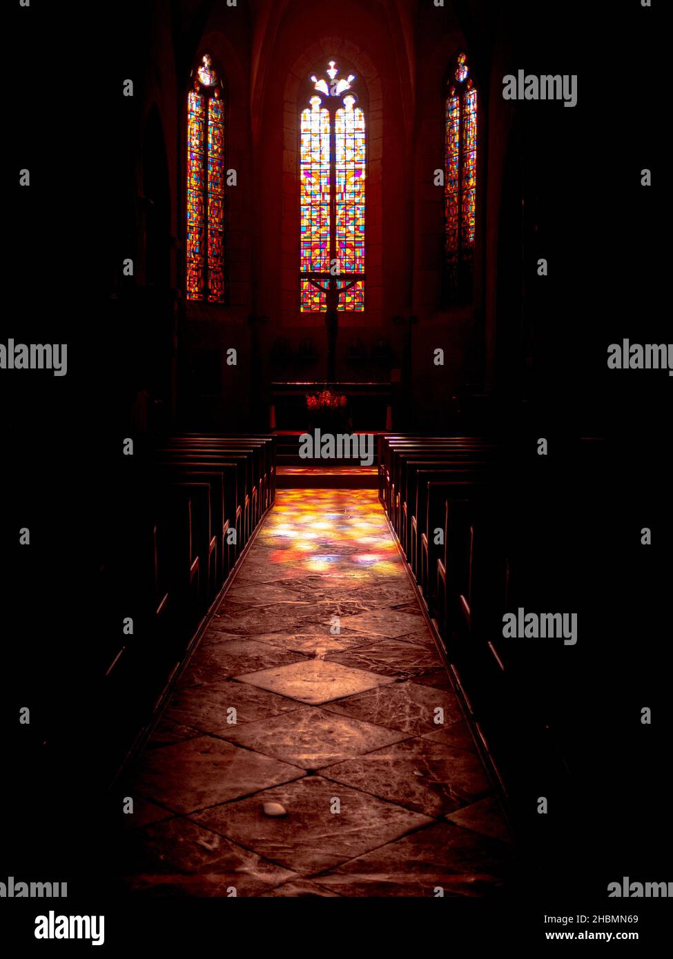 Abstracta vidrieras multicolores de la iglesia de Saint-Côme-d'Olt en Francia vista desde el interior sin gente y con proyección de los colores vidrieros en el Foto de stock