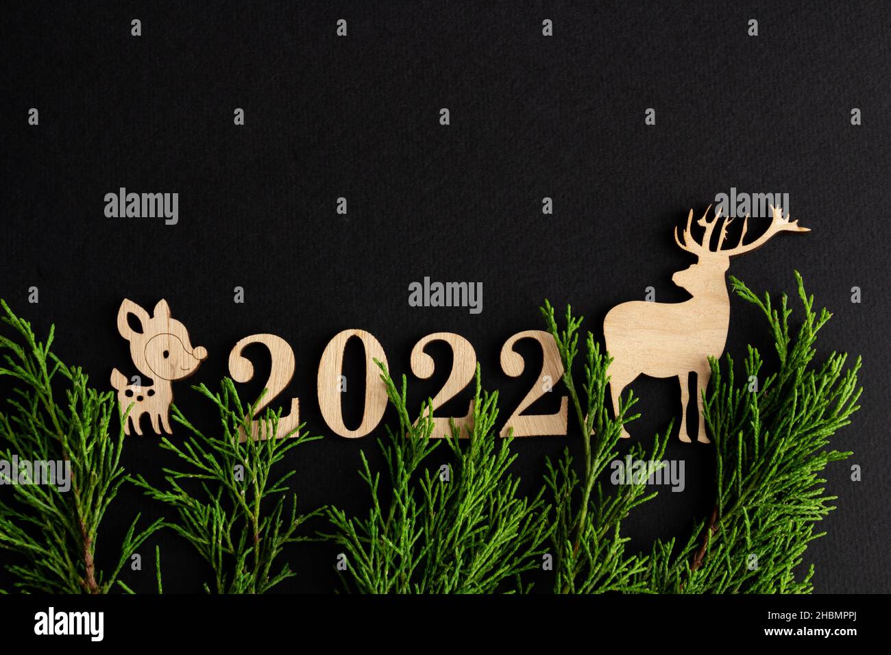 2022, composición de navidad sobre fondo negro, ciervo de madera, espacio de copia Foto de stock